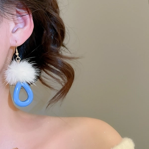 Detailed shot of resin teardrop earrings with fluffy white fur pompom and gold hooks