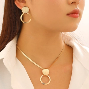 Detail of gold geometric necklace and earrings set with brushed metal texture