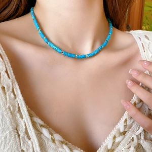 Detail of blue bead and gold accent choker necklace worn on a model's neck