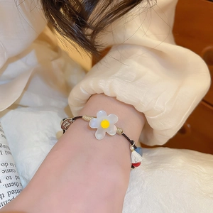 Détail d'un bracelet floral en résine fait main avec cordon tressé brun et breloque