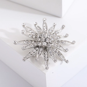 Elegant silver sunflower brooch with sparkling crystals on minimalist white geometric props