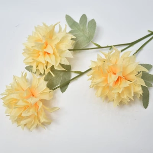 Detail of yellow silk pompon mum with three lifelike flower heads and green leaves