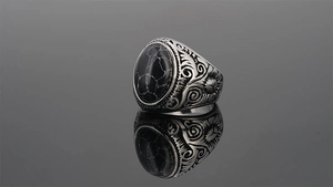 Macro detail of men's vintage ring featuring black oval stone and intricate silver engraving