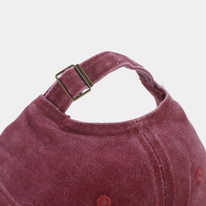 Detail of burgundy corduroy baseball cap showing adjustable bronze metal buckle back