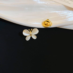 Close-up of golden butterfly brooch with cat-eye wings on black velvet and white satin