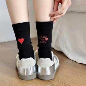Detail view of black crew socks with red heart and Follow your heart embroidery