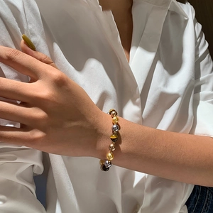 Gros plan d'un bracelet vintage français en œil de tigre et perles au poignet d'une femme
