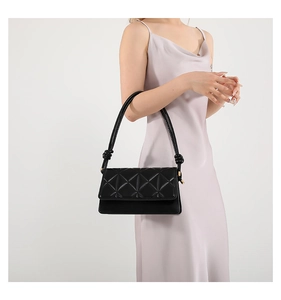 Detail of black PU leather shoulder bag with geometric quilted pattern and knotted strap