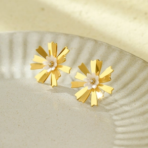 French minimalist hollow flower earrings in gold and white on a ceramic tray