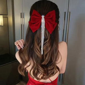Detail of red velvet bow hair clip with long sparkling rhinestone tassels on hair