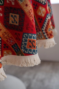 Close-up of red American style jacquard tablecloth with beige fringe and geometric patterns