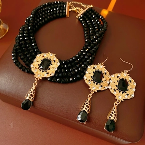 Macro shot of vintage gold-tone jewelry set with black beads and teardrop pendants