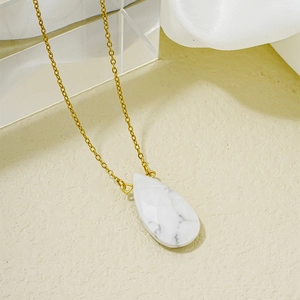 Collier élégant en chaîne dorée avec pendentif goutte en pierre blanche sur fond satin