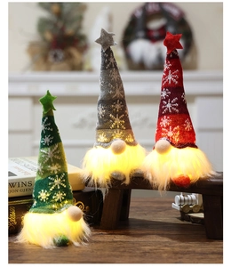 Close-up of three glowing Christmas gnomes with knitted hats in warm indoor holiday decor