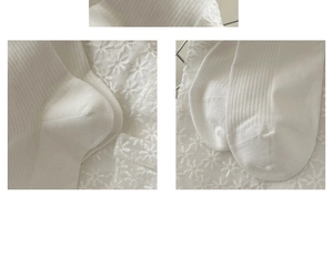 Close-up of white cotton ribbed socks showing texture and stitching on lace background