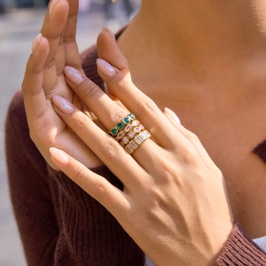 Detail of stacked gold-plated rings with colorful zircon stones worn by a model