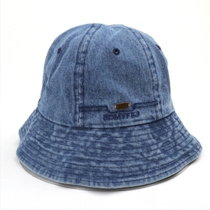 Detail of blue denim bucket hat featuring metal logo plate and reinforced brim stitching