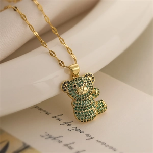 Macro shot of gold necklace with bear pendant set with green and black gemstones