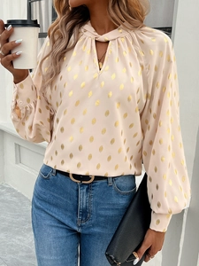 Detail of light pink long sleeve shirt with gold polka dots and tie-neck design
