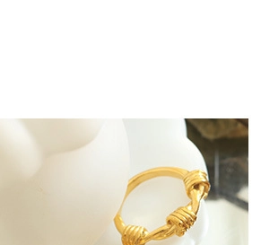 Close-up of golden titanium steel oval knot ring with polished metal texture