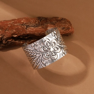 Detailed macro view of vintage silver wide cuff with intricate embossed floral patterns