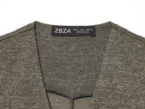 Detail des V-Ausschnitts mit Markenetikett auf olivgrünem gestricktem ärmellosem Kleid