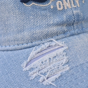 Close-up of distressed brim and navy ONLY embroidery on light blue washed denim baseball cap