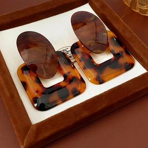 Detail view of tortoiseshell resin geometric earrings with silver pins in a jewelry box