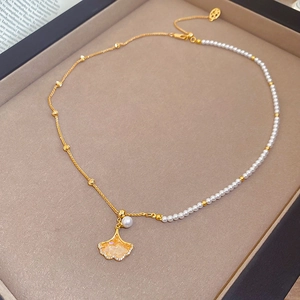 Detailed view of maple leaf pearl necklace with gold chain on grey display tray