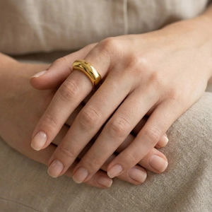 Detailed view of chunky 18k gold plated dome ring with polished glossy finish on finger