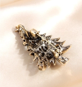 Detailed back view of golden Christmas tree brooch with secure pin clasp on silk