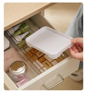 Detailed view of placing white drawer dividers into clear storage bins for organization