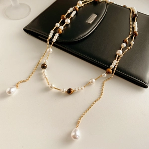Detail of vintage necklace with pearls, brown tiger eye beads, and gold chain on leather