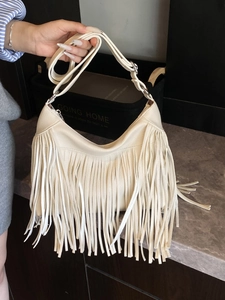 Chic cream-colored crossbody bag with trendy lychee grain leather and long fringe details