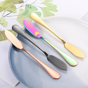 Lot de quatre couteaux à beurre colorés en acier inoxydable sur une assiette blanche