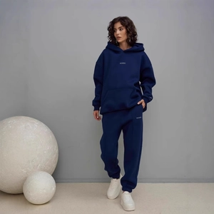 Detail of dark blue hoodie and jogger set in premium cotton on a model with studio props