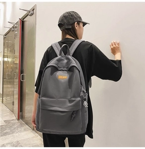 Gray minimalist large capacity backpack shown from the back on a model in a modern hallway