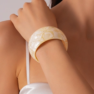 Close-up of wide ivory acrylic bangle with marble texture on model's wrist