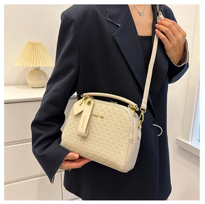 Detail of a creamy white crossbody bag with woven texture and gold-tone hardware on a model