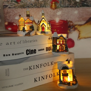 Macro detail of lighted Christmas resin houses with warm LED glow and snow accents
