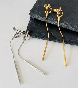 Detail of elegant 18k gold and silver knot drop earrings with snake chain tassels