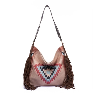 Macro shot of bohemian woven shoulder bag featuring fringe details and geometric pattern