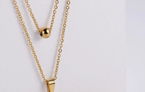Detail of gold-plated double-layer chain necklace with spherical and geometric pendants