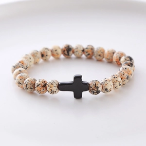 Detailed shot of beaded bracelet with spotted natural stones and a black cross pendant