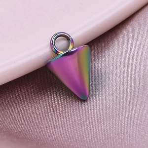 Macro shot of a rainbow-colored conical metal pendant on soft pink silk fabric texture