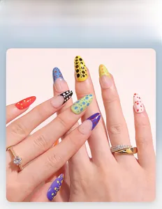Close-up of short almond press-on nails featuring colorful French polka dots and gold rings