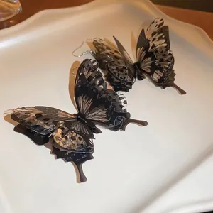 Vintage 3D butterfly drop earrings with layered black translucent wings on a white plate