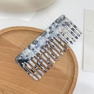 Retro acetate wide-tooth hair comb with elegant marble pattern on a wooden tray