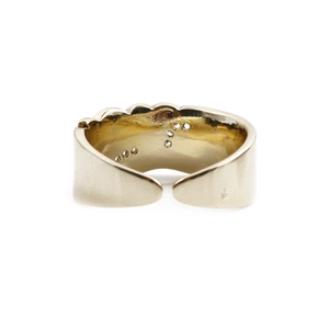 Detail view of adjustable gold-plated ring showing wavy edges and smooth interior