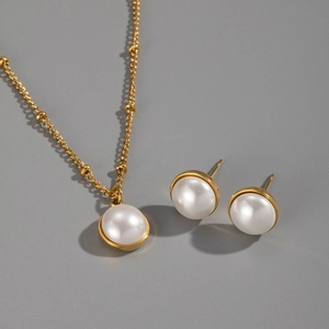 Macro detail of gold beaded necklace and stud earrings with elegant pearl settings